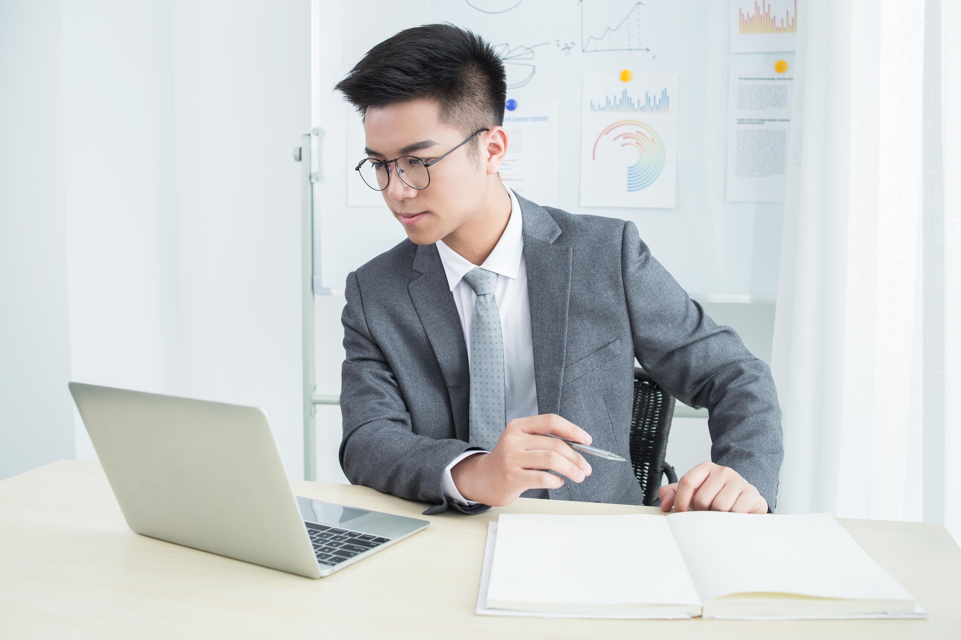 Uomo d'affari asiatico che lavora sul computer portatile e prende appunti